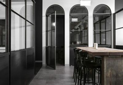 Minimalist hallway featuring arched glass doorways and a high-top wooden communal table.