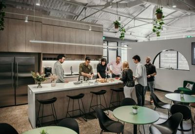 Group of people gathering and collaborating around a large kitchen island.