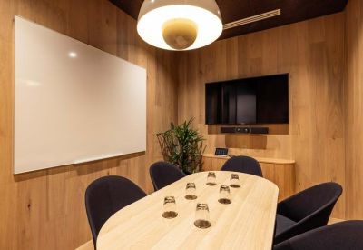 Small meeting room with wood-paneled walls, oval table, and a large television screen.