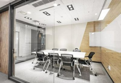 Bright glass-walled meeting room with a white conference table and ergonomic black chairs.