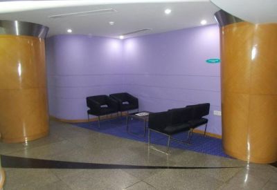 Lounge area with purple walls and black armchairs between large wooden pillars.