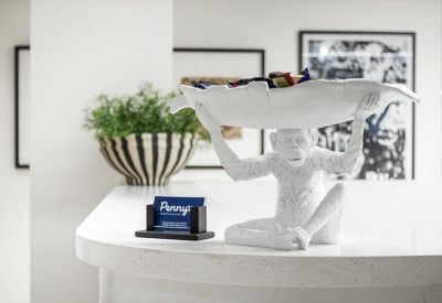 Whimsical white monkey sculpture holding a tray on a white reception counter.