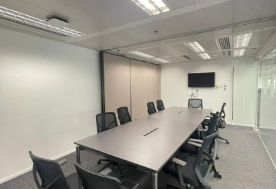 Spacious boardroom featuring a long grey table and black mesh ergonomic chairs.