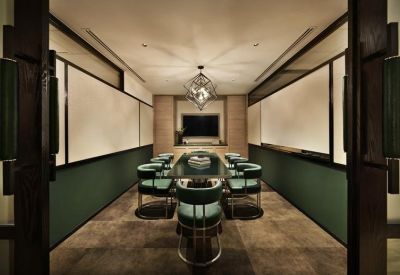 Sophisticated meeting room with emerald green chairs, a glass table, and a statement chandelier.