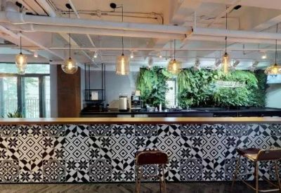 Cafe-style bar featuring a black and white patterned tile facade and a lush green plant wall.