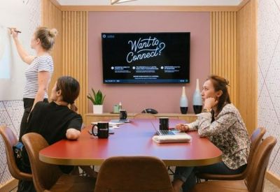 Creative meeting room with a large screen, whiteboard, and pink accent wall.