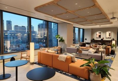 Spacious lounge with orange sectional sofa, designer lighting, and floor-to-ceiling city views.