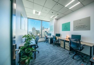 Modern private office with three workstations, ergonomic chairs, and large window overlooking the city.