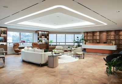 Wide-angle view of a grand reception area with a large lightbox ceiling and herringbone wood floors.