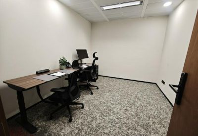 Compact two-person private office with ergonomic chairs and patterned carpet.