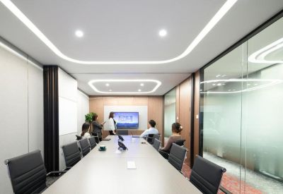 Professional boardroom with a long white table, integrated screen, and sleek glass walls.