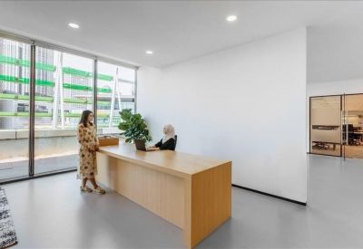 Modern lobby area with a wooden reception desk and views of the street through glass walls.