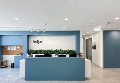 Bright reception area with a blue front desk and branded white wall background.