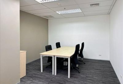 Four-person private office with light wood desks and black ergonomic chairs.