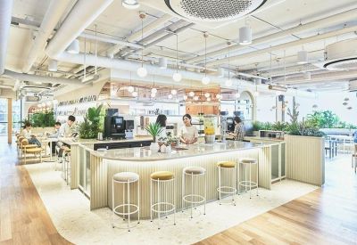 Sleek cafe area with a curved white counter, bar stools, and lush indoor greenery.