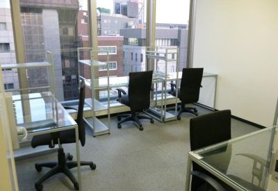 Glass-walled office space with multiple workstations and city views.