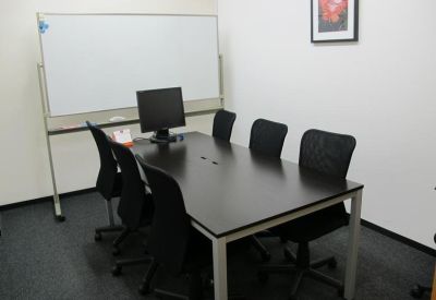 Private meeting room with a dark wood table, six chairs, and a whiteboard.