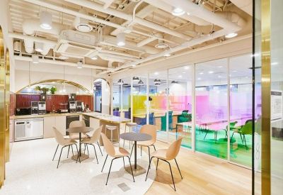 Open office layout with colorful glass partitions and small cafe tables for informal meetings.