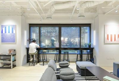 Bright breakout space with stools at a window counter and a cozy lounge area.
