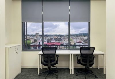 Bright two-person office suite with city views through large windows.