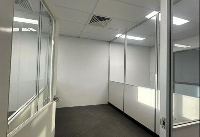Internal view of a private office suite with glass walls and grey carpeting.