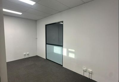 Clean, bright private office with white walls, recessed lighting, and a frosted window panel.
