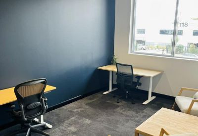 Private office suite featuring a blue accent wall, two workstations, and a small sitting area.