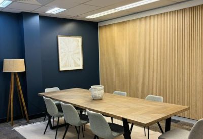 Sophisticated meeting room with a large wooden table and grey upholstered chairs.