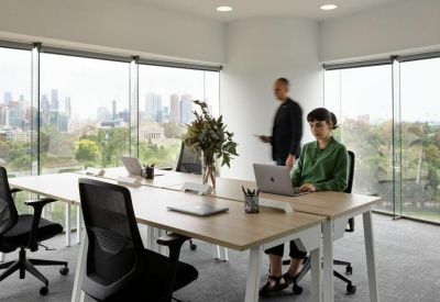Bright shared workspace with wooden desks, ergonomic chairs, and city views.