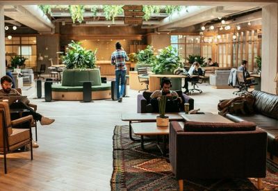 Spacious communal lounge with diverse seating, indoor trees, and warm lighting.