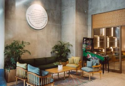 Lobby area featuring mid-century modern armchairs, a pinball machine, and industrial concrete walls.