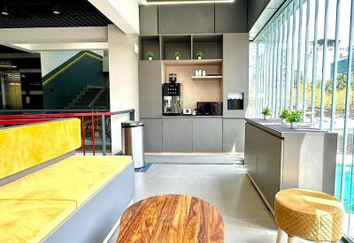 Bright breakroom with a wooden coffee table, yellow cushioned seating, and coffee station.