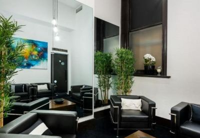 Modern lounge area with black leather armchairs, a wooden coffee table, and indoor plants.