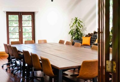Large boardroom featuring a long timber table, tan leather chairs, and polished wood floors.