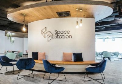 Modern reception lounge with blue velvet armchairs and branded curved feature wall.