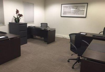 Private internal office suite with dark wood desks, black ergonomic chairs, and neutral carpet.