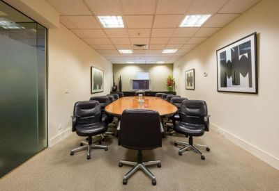 Professional boardroom with a large wooden table, black leather chairs, and framed artwork.