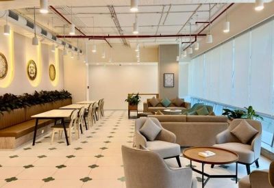 Spacious communal lounge with plush grey armchairs, café seating, and decorative wall clocks.