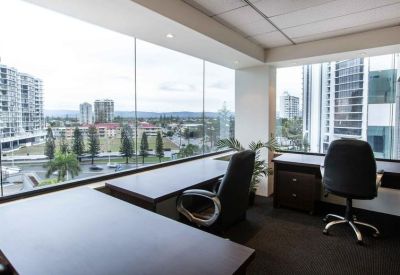 Bright corner office with floor-to-ceiling windows overlooking the city and coastline.