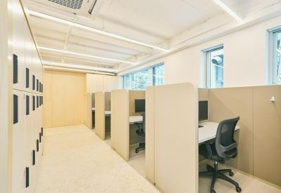 Private workstation booths separated by light wood partitions next to a wall of lockers.