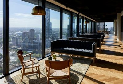 Bright lounge area with panoramic city views, herringbone timber floors, and stylish mid-century seating.