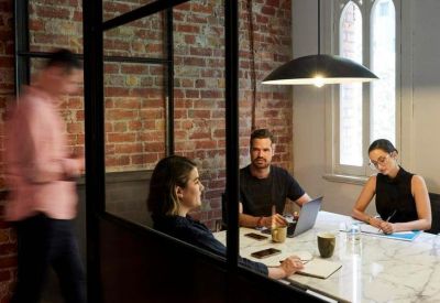 Collaborative workspace with exposed brick walls, marble table, and glass partitions.