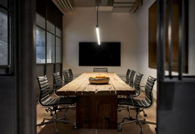 Boardroom featuring a large rustic timber table, leather chairs, and a sleek pendant light.