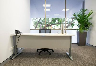 Private office suite with a white desk, ergonomic chair, and large window.