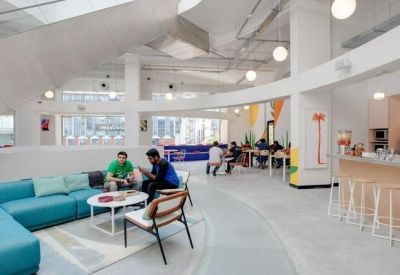 Bright coworking area with blue seating and a curved white architectural beam.