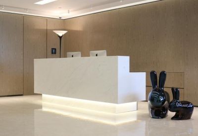 Sleek white marble reception desk with minimalist wood paneling and decorative bunny sculptures.