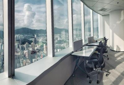 Coworking space with dedicated desks positioned alongside floor-to-ceiling windows.