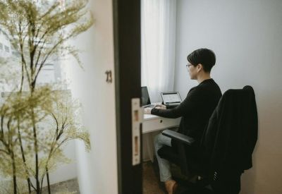 Private office suite with a person working at a desk beside a tall indoor plant.
