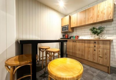 Modern kitchen and breakout area featuring wooden cabinetry and breakfast bar.