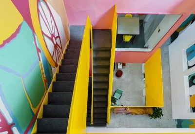 High-angle view of a colorful stairwell area with yellow railings and vibrant wall murals.